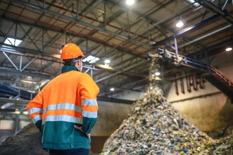 Man in orange vest by garbage pile highlights food & beverage waste services in Franklin, TN