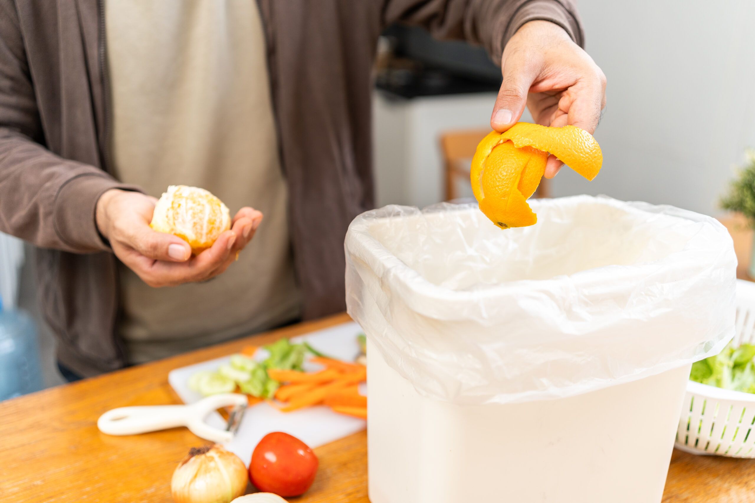 Man places orange in container, highlighting pre-consumer food waste importance in Franklin, TN