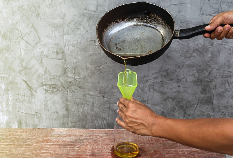 Person pouring used cooking oil from a frying pan into a bottle for disposal in Franklin, TN