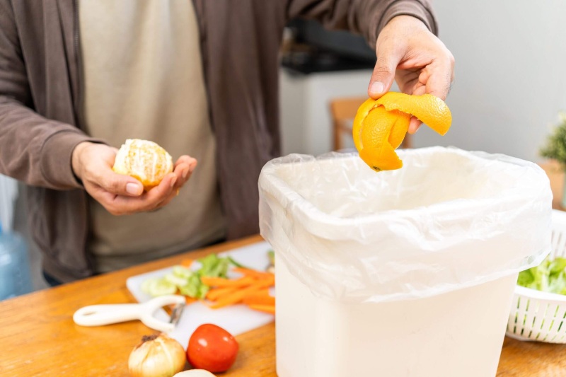 A man places orange slices in a container, showing the importance of food waste in Franklin, TN