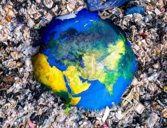 Earth illustration surrounded by piles of plastic waste and trash 