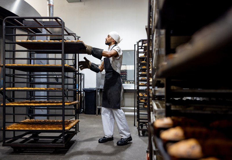 Bakery worker arranging trays of baked goods for food waste management in Pennsylvania