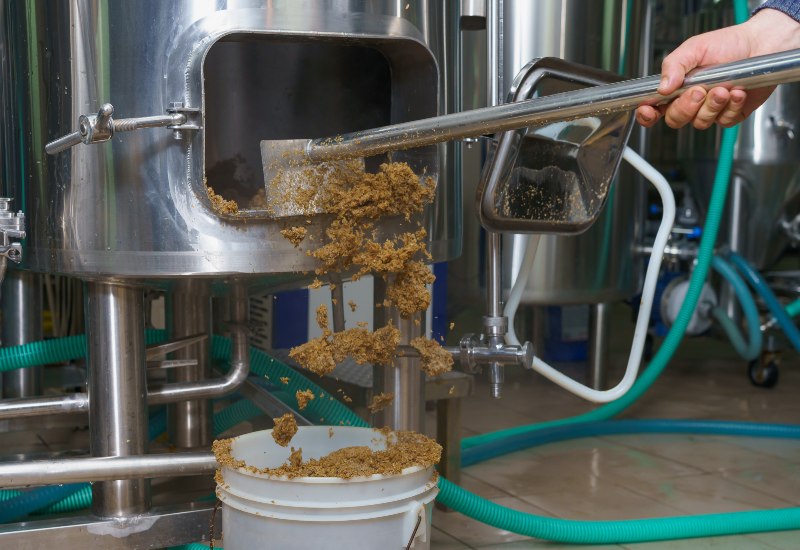 A worker removing processed material from a stainless steel tank in Virginia